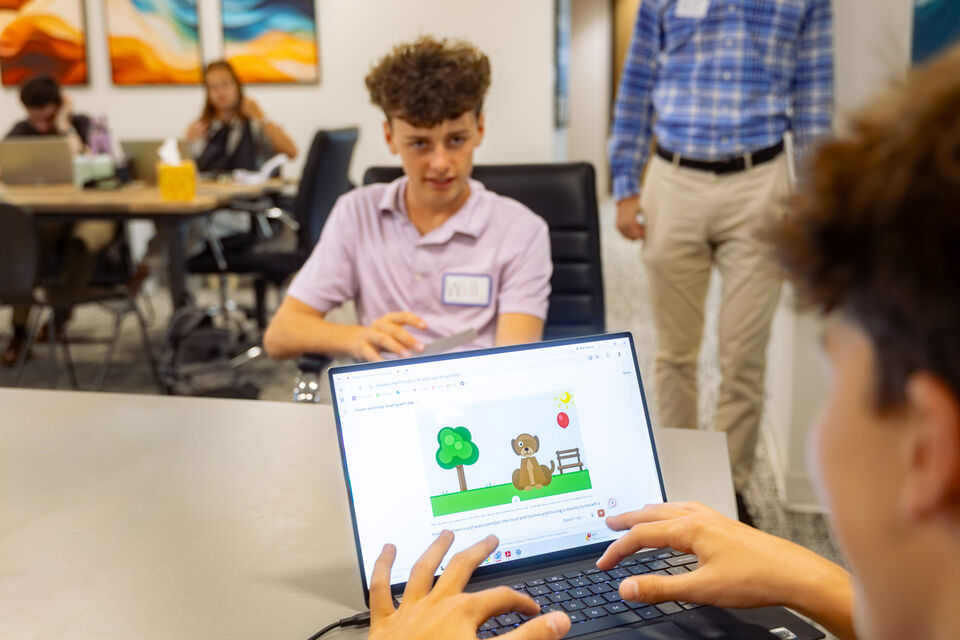 A student presenting an AI scene from a laptop to the room