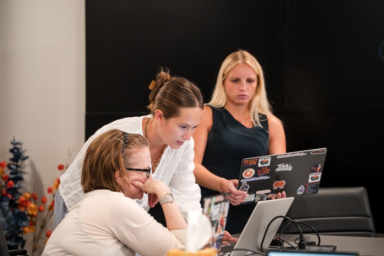 Three PhoenixTeam practitioners review work together on a laptop